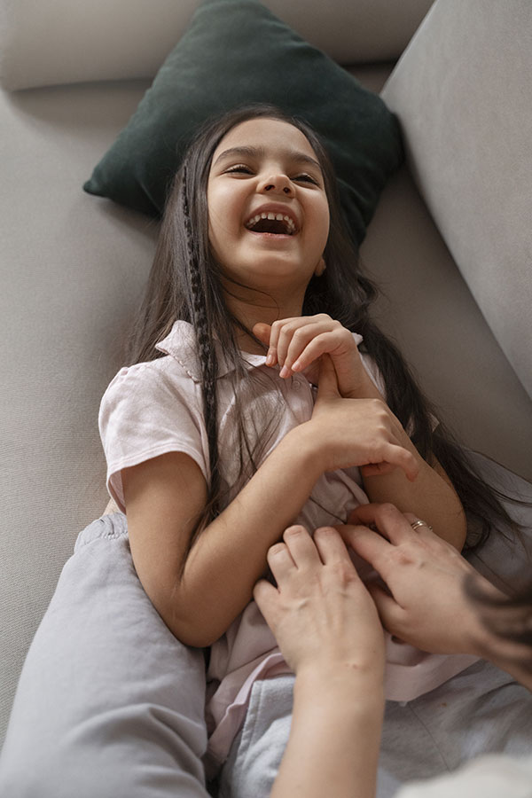 Mom tickling daughter on couch